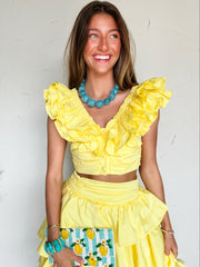 Woman wearing a yellow ruffled set with a white background