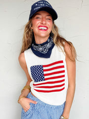Woman wearing a knit tank top with an American flag design, a navy cap, and a bandana against a white background.
