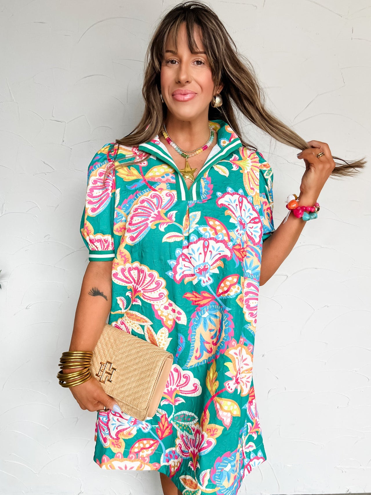 Woman wearing a colorful floral dress against a white wall