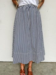 Person wearing a black and white striped skirt against a white wall.