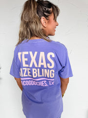 Person wearing a purple t-shirt with 'Texas Size Bling' text on a white background
