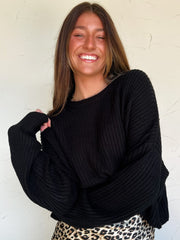 Woman wearing a black sweater and leopard print skirt against a white wall