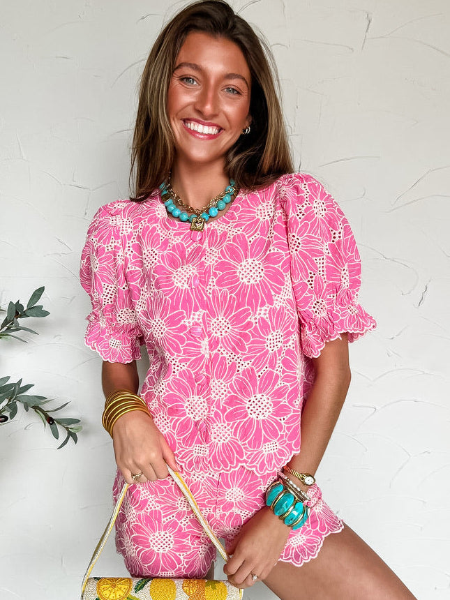 Woman in a pink floral set holding a lemon-patterned bag against a white background