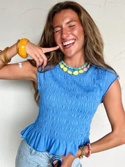 Woman wearing a blue top with colorful accessories against a white background