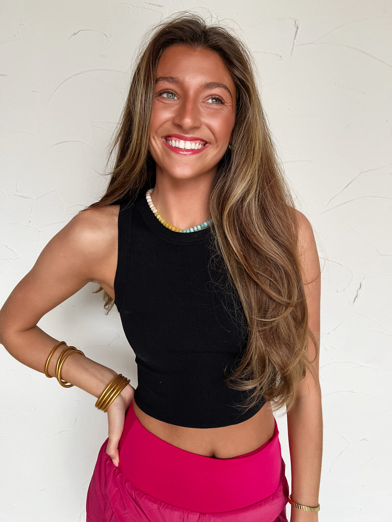 woman wearing a black ribbed tank top with pink athletic shorts