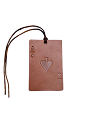 A rectangular leather card tag designed to look like an Ace of Spades playing card, featuring an embossed heart in the center and a dark brown leather hanging loop with frayed ends, shown on a plain white background.