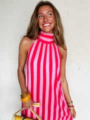 Woman wearing a pink and hot pink striped halter neck midi dress against a white background