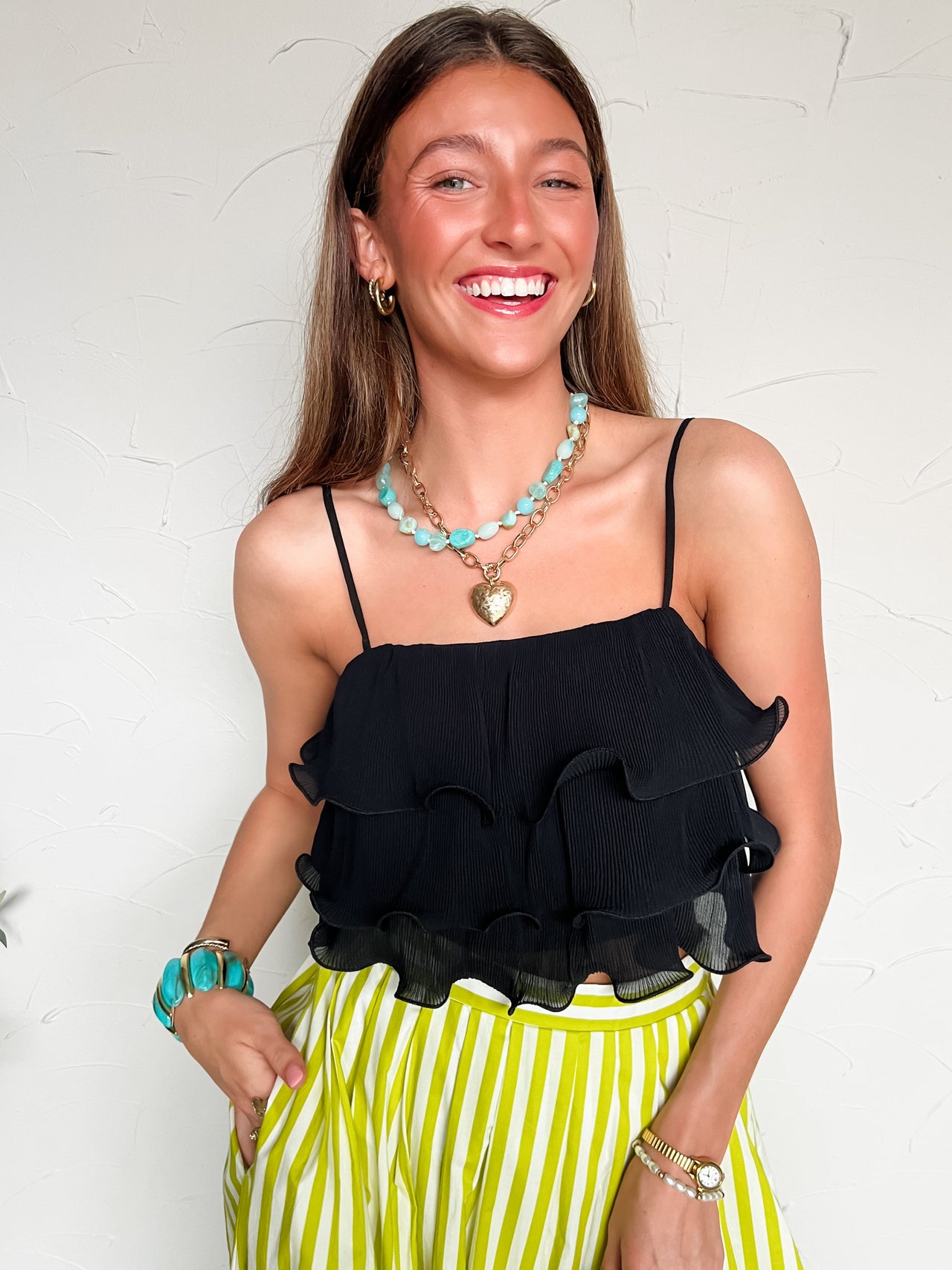 Woman wearing a black ruffled top and striped skirt with a white background
