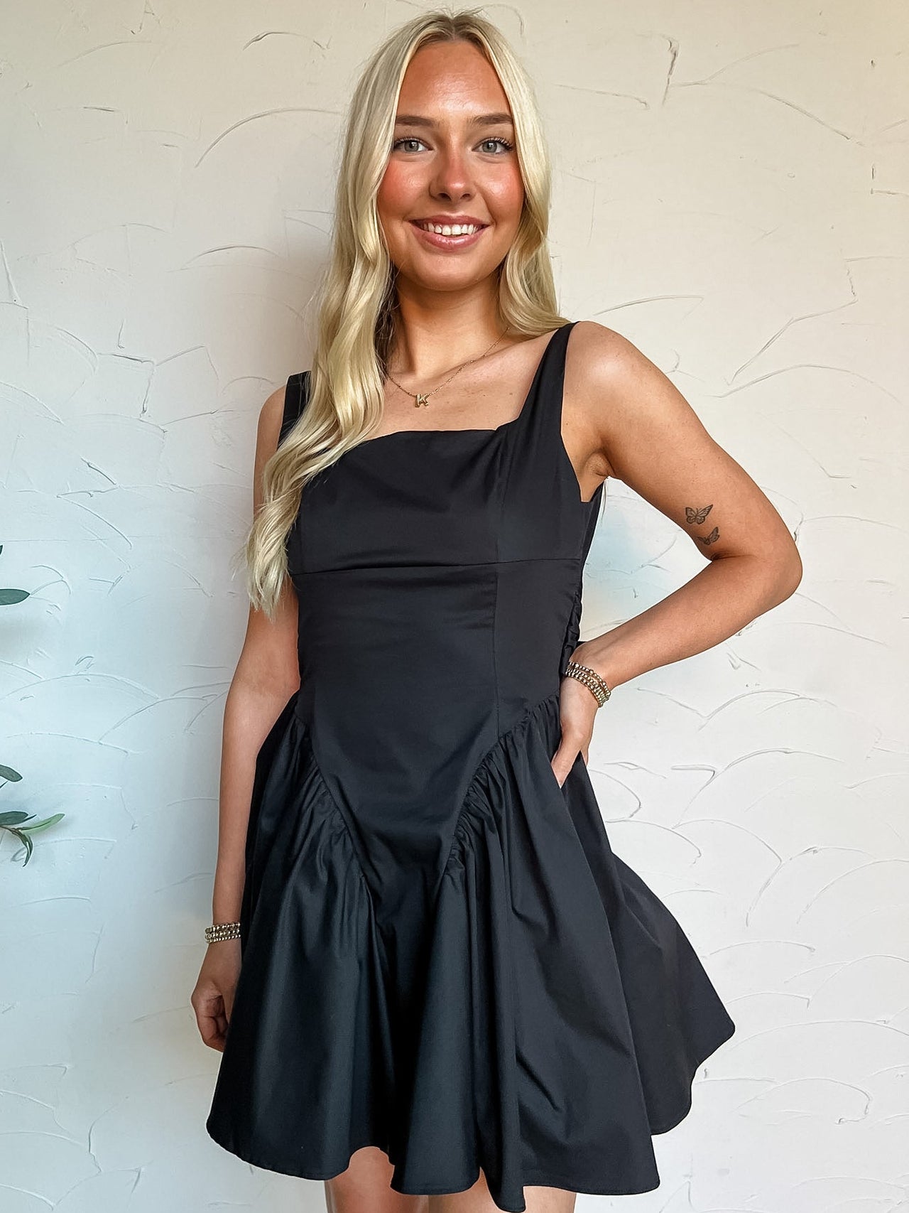 Woman wearing a black dress against a white wall