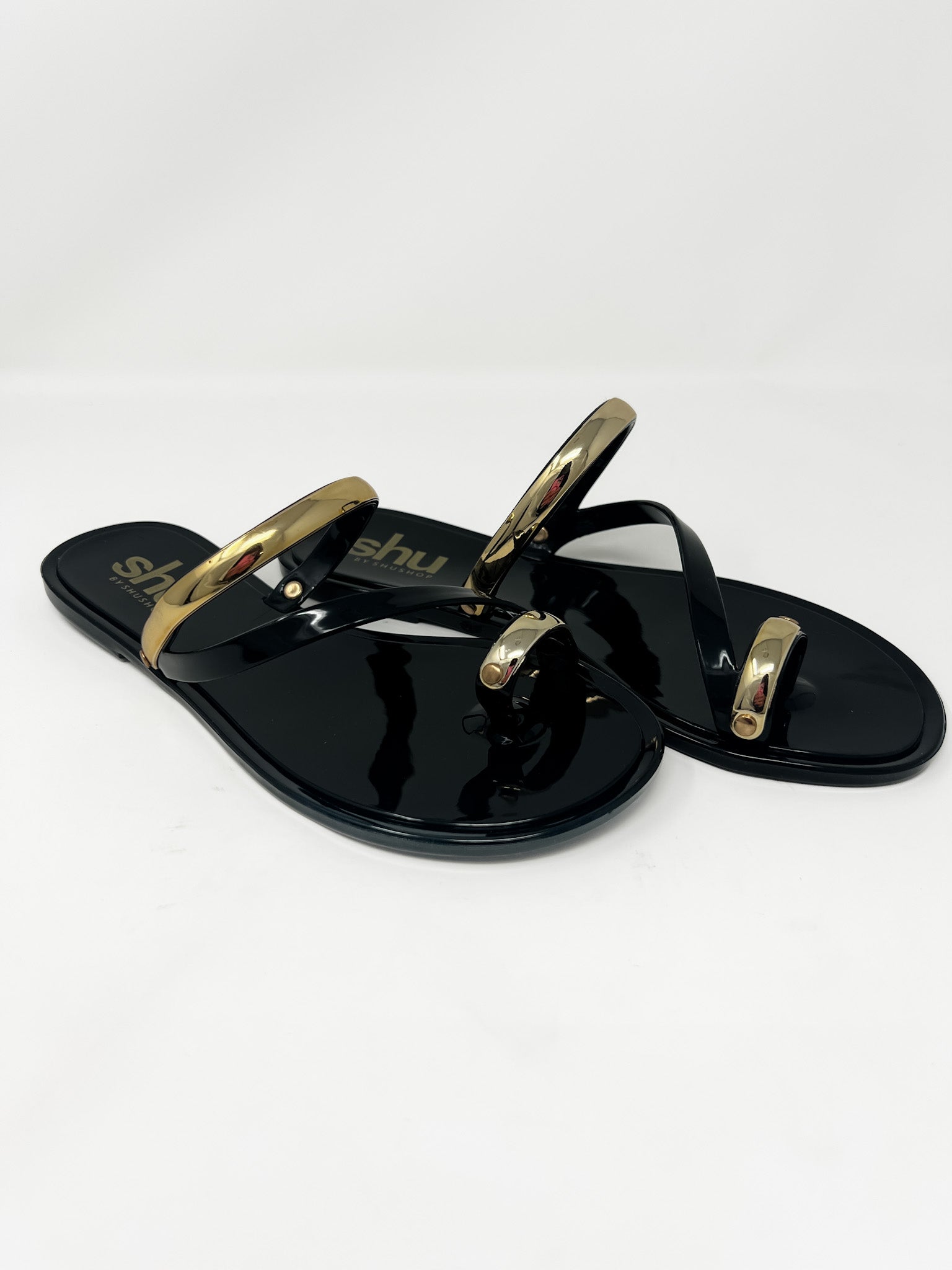 Black sandals with gold straps on a white background