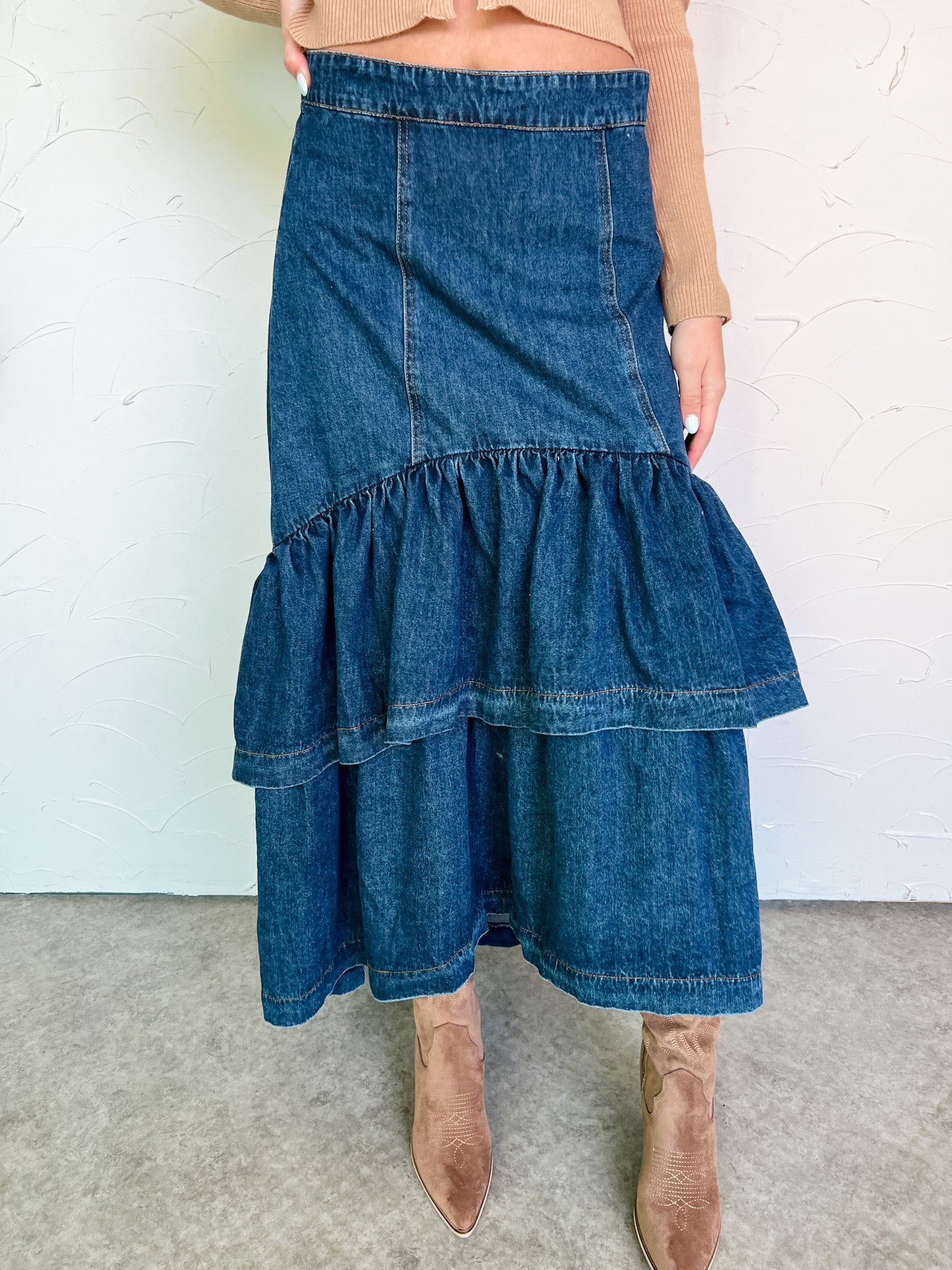 Denim skirt with ruffled layers worn by a person against a white background