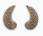 A pair of crescent-shaped adhesive ear plugs with a black leopard print pattern on a beige background, outlined in white.