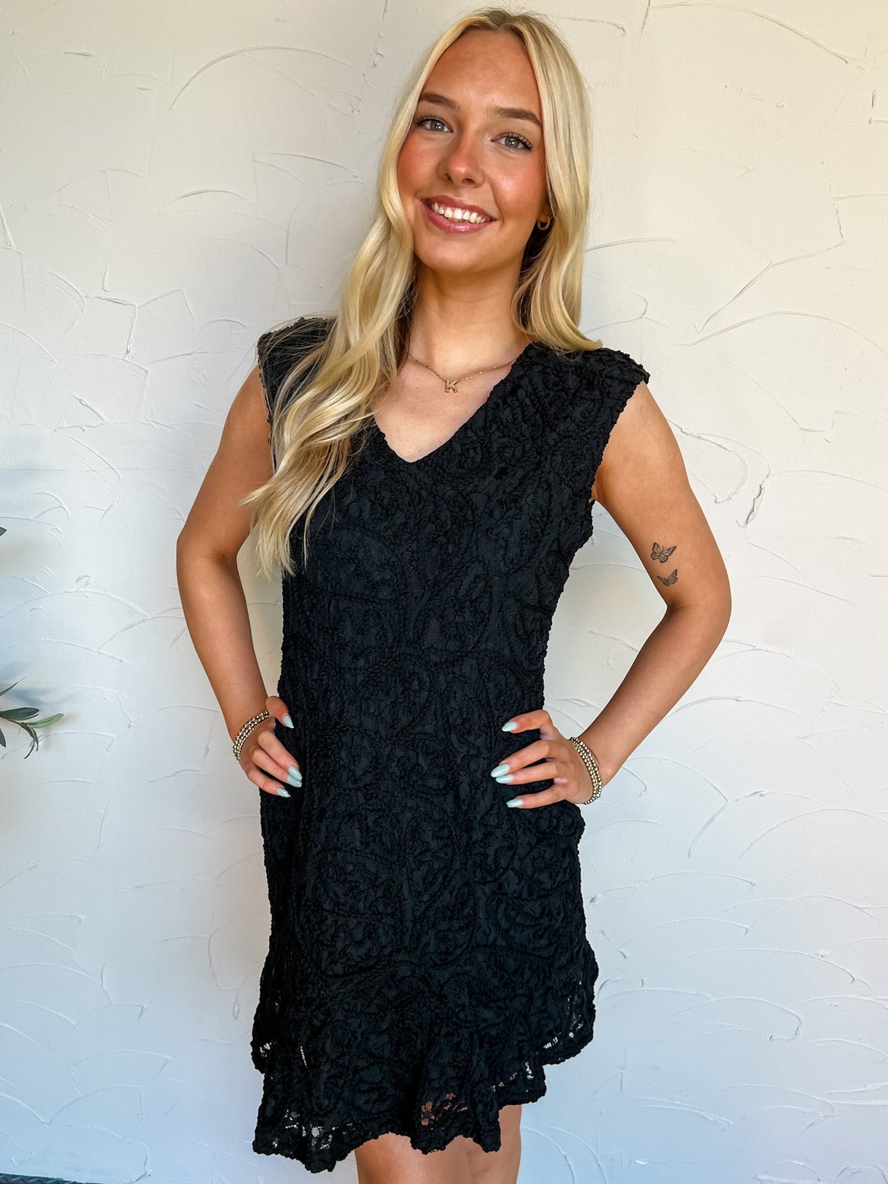 Woman wearing a black lace dress against a white wall