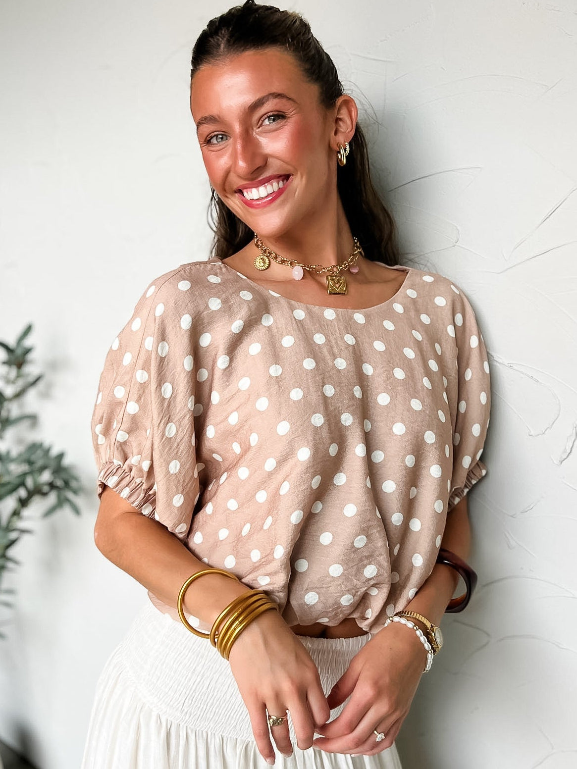 Woman wearing a beige blouse with white polka dots against a light background