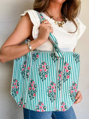 Person holding a floral and striped bag against a plain background