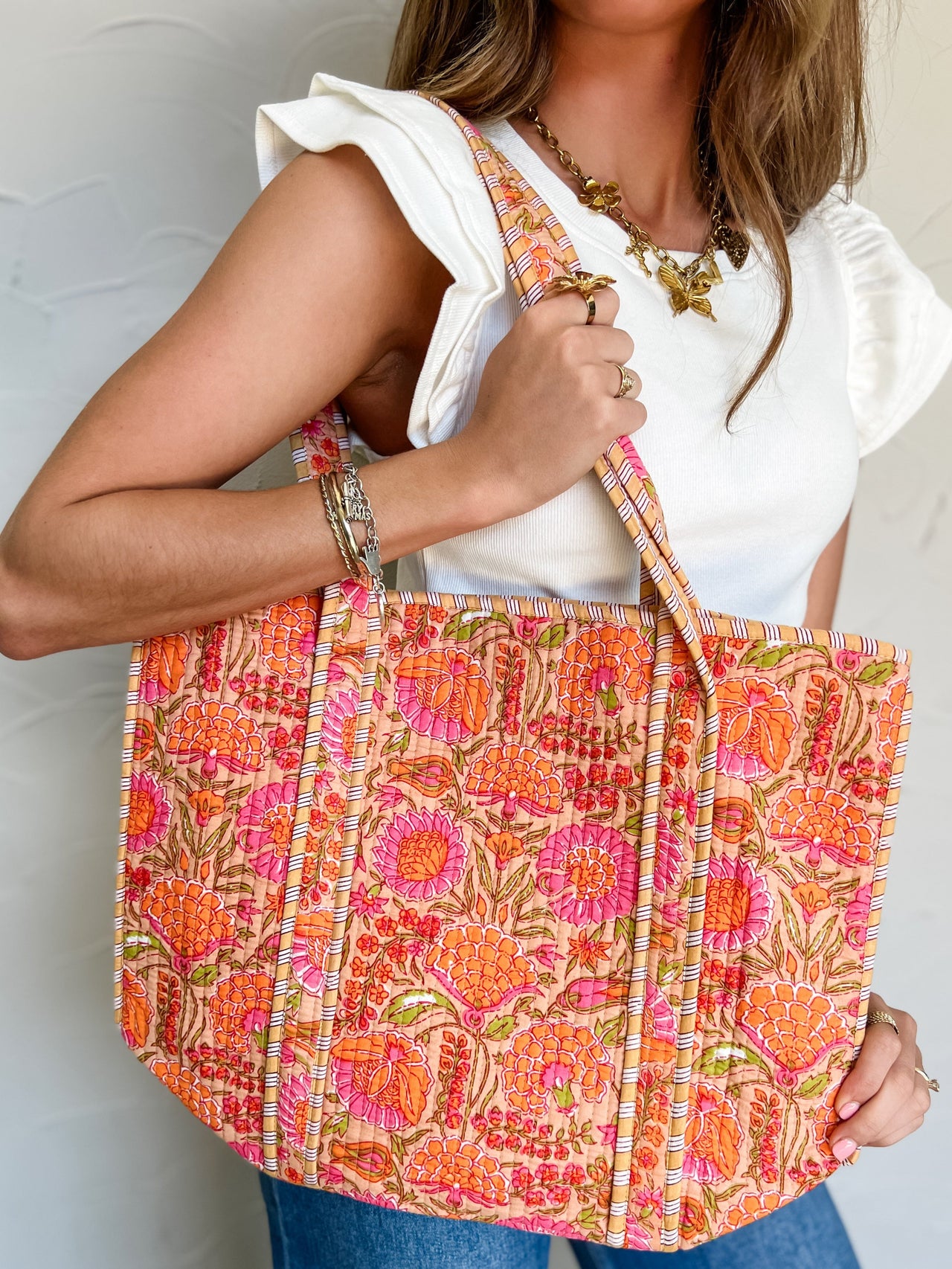 Woman holding a colorful floral-patterned bag against a plain background