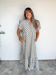 Lesly modeling an Entro 100% cotton midi dress in size Large, featuring dark polka dots over a light fine-check background, short puff sleeves, gathered cuffs, a ruffled stand collar, split neckline, upper-front buttons, side pockets, and a gathered ruffle hem, styled with white sneakers and gold-tone bracelets.