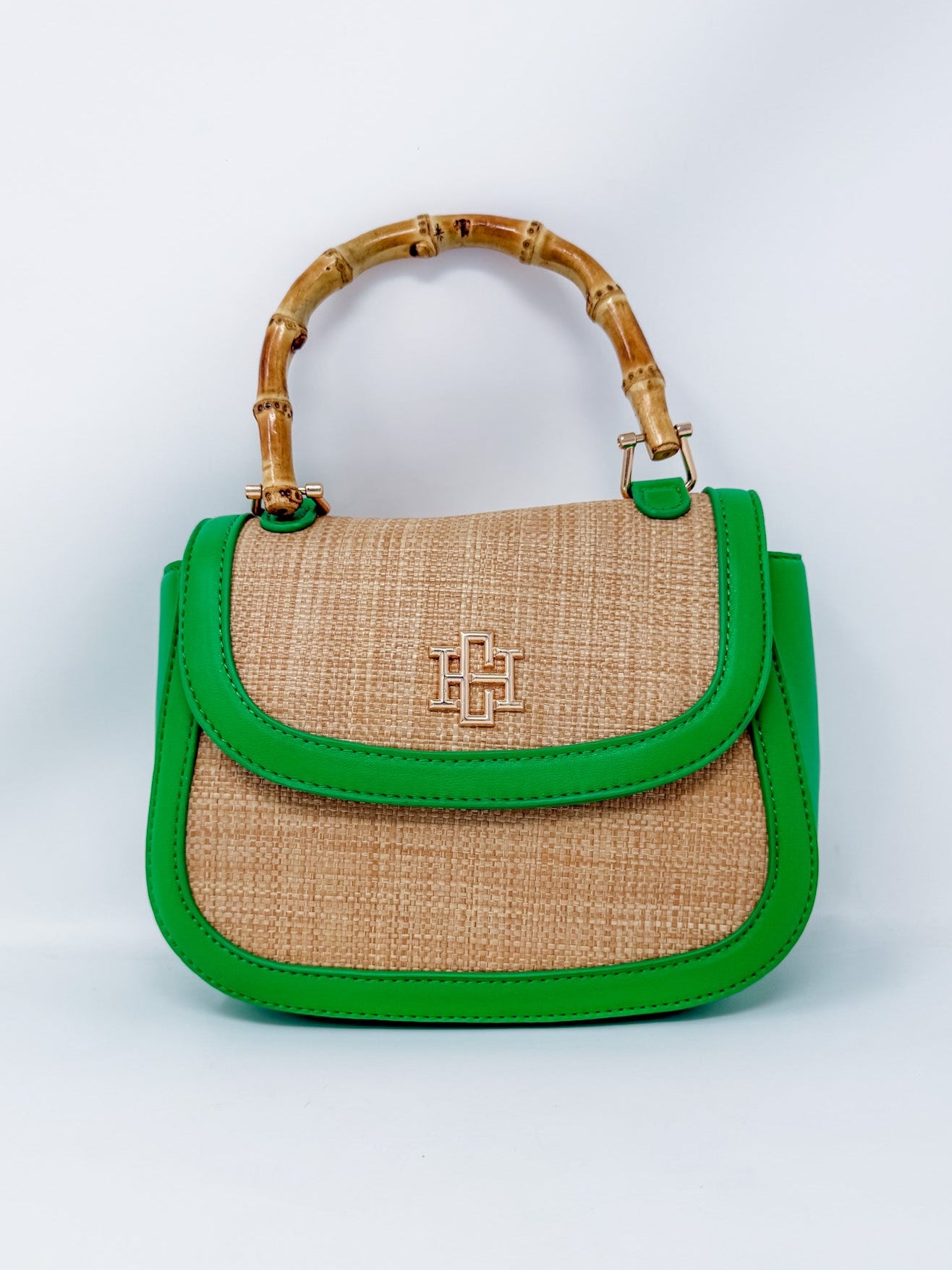 Handbag with green trim and bamboo handle on a white background