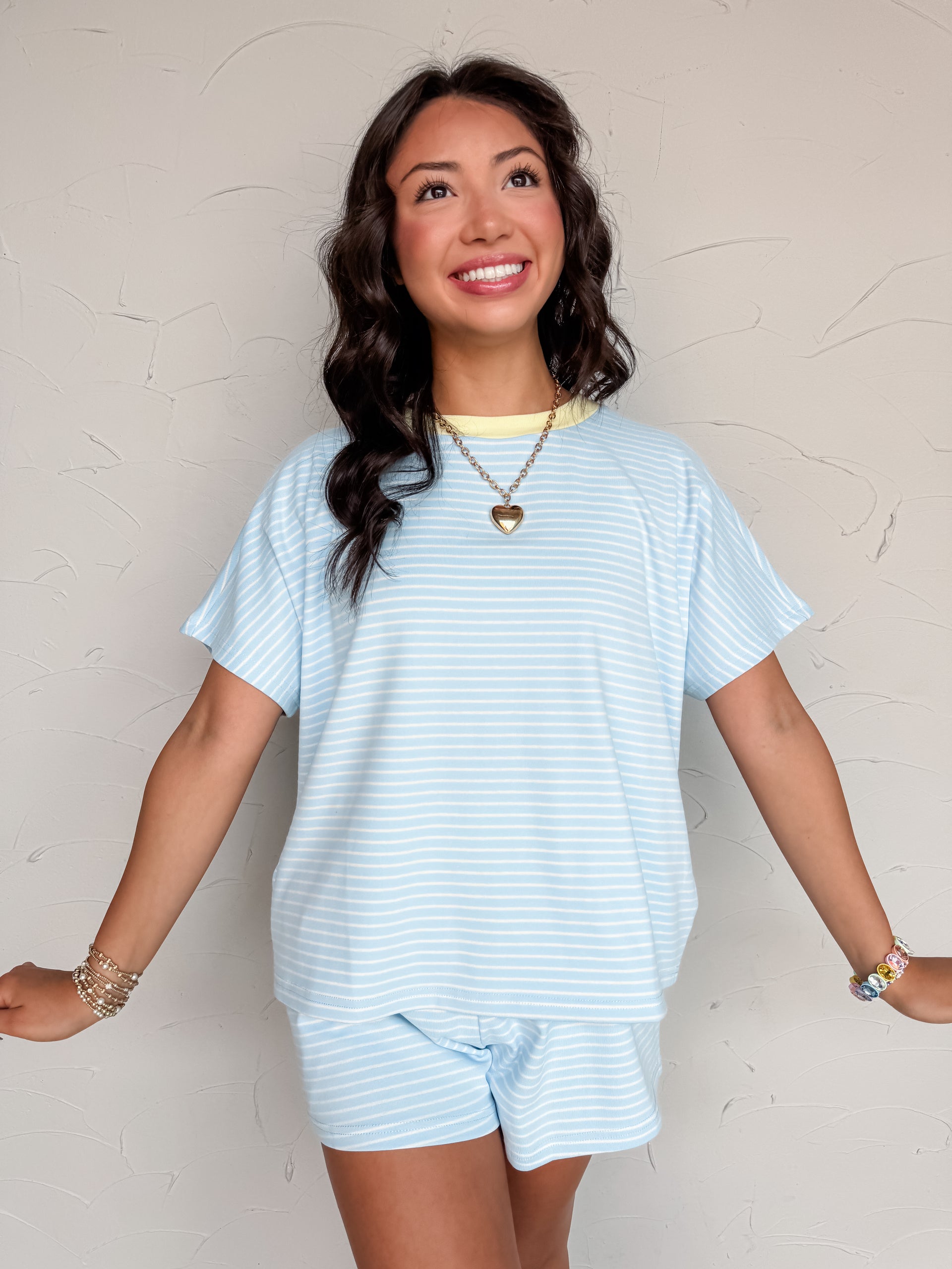Woman wearing a light blue striped outfit against a plain background