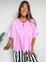Woman wearing a pink oversized shirt and black and white striped pants against a white background