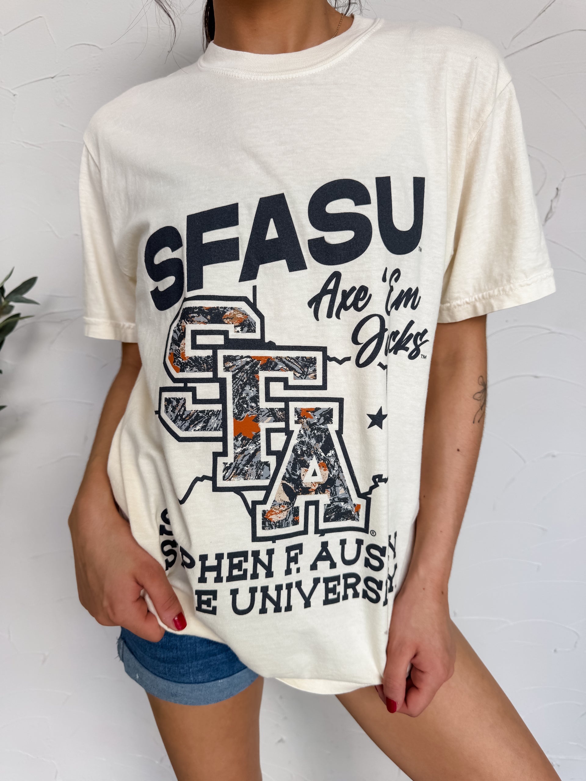Person wearing a white t-shirt with 'SFASU' and 'Stephen F. Austin State University' text on a light background
