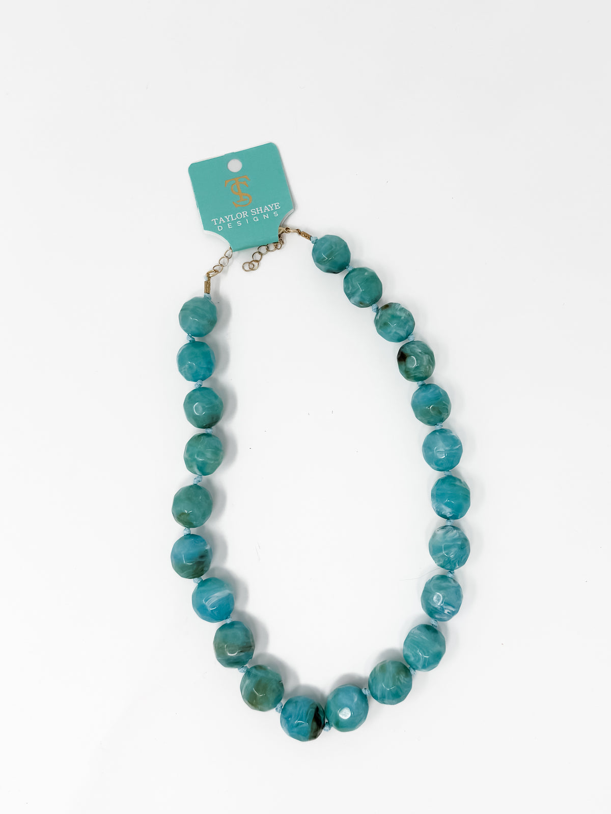 A turquoise beaded necklace with a gold-tone clasp and a teal brand tag, displayed on a clean white background.