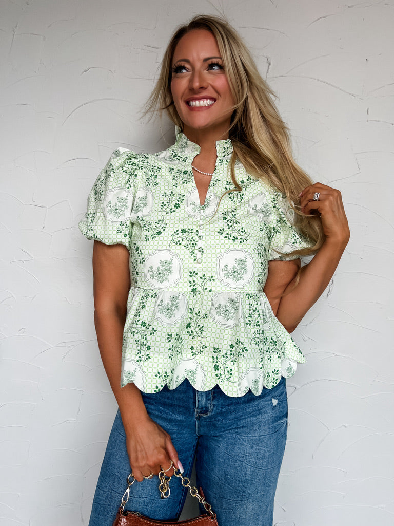 Woman wearing a green floral blouse against a white wall