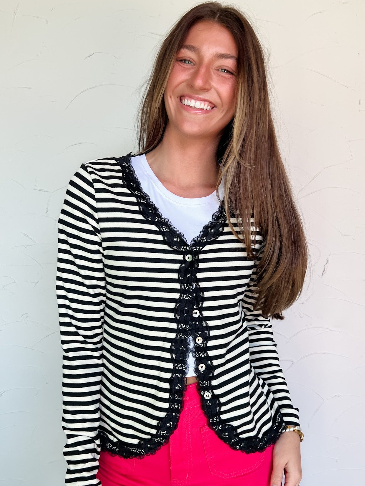 Woman wearing a black and white striped cardigan with lace details against a light background