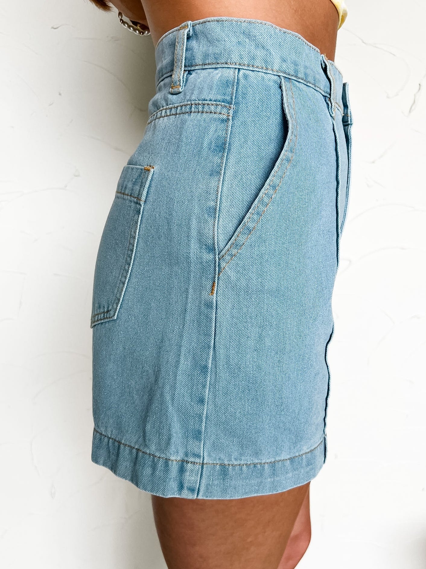 Light blue denim shorts worn by a person on a white background