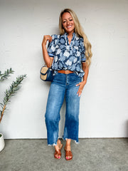 Girl in floral top in front of plain background 