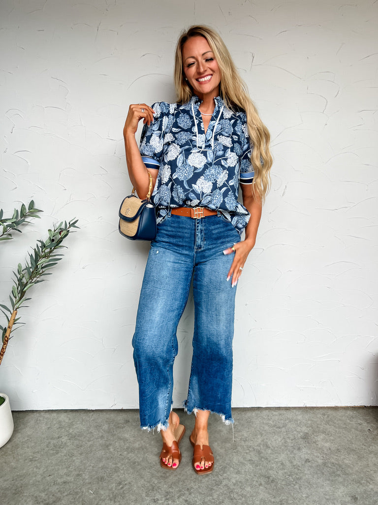 Girl in floral top in front of plain background 
