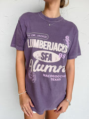 Person wearing a purple 'Lumberjacks SFA Alumni' t-shirt against a white background