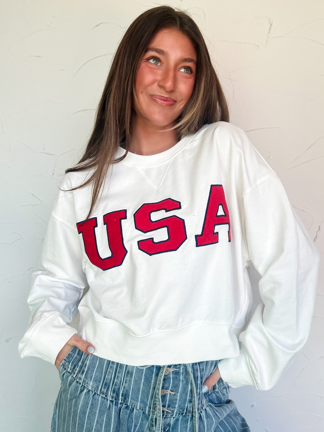 Person wearing a white sweatshirt with 'USA' printed in red on a light background