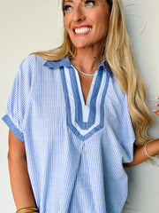 Woman wearing a blue and white striped shirt against a plain background