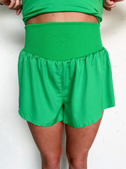 Green shorts worn by a person on a white background
