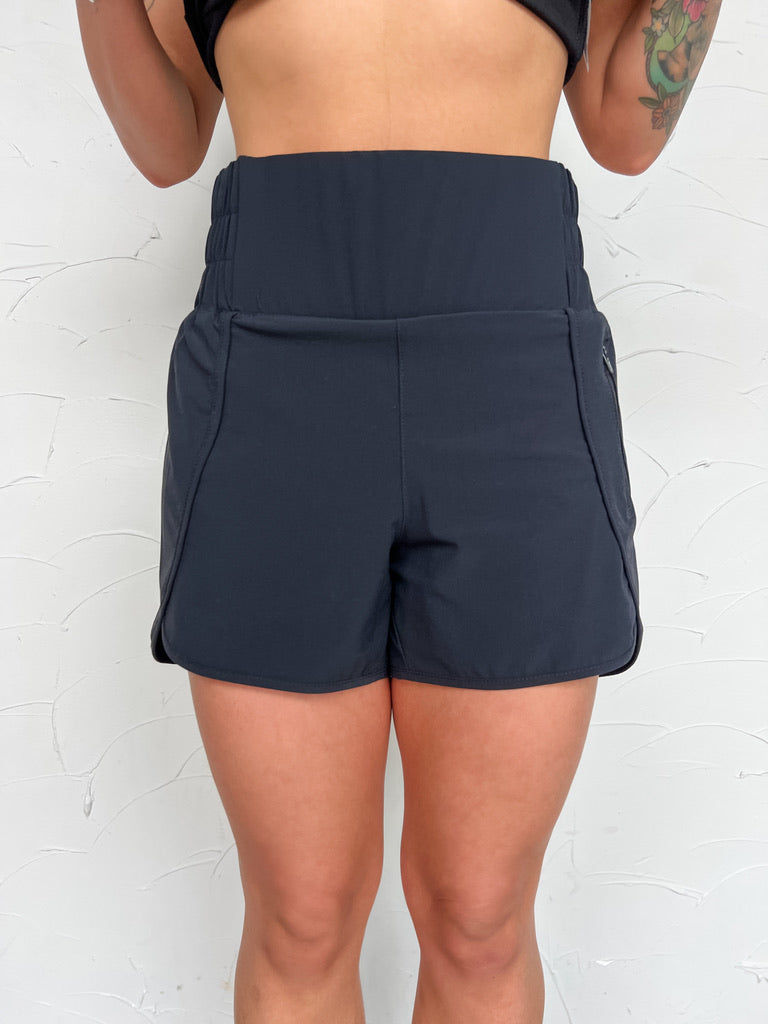 Girl in black shorts in front of plain wall 