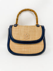 Handbag with straw design and navy trim and bamboo handle on a white background