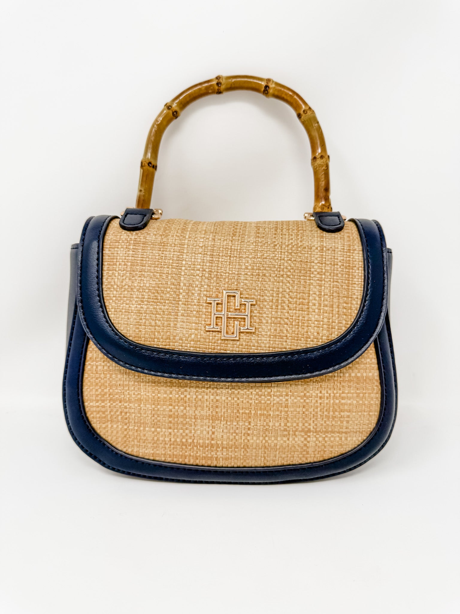 Handbag with straw design and navy trim and bamboo handle on a white background
