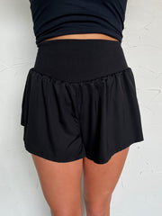 Person wearing black shorts and a black top against a white background