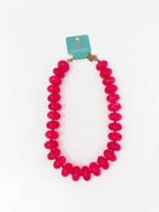 A bright pink chunky beaded necklace with a gold-tone clasp, displayed on a white background with a teal brand tag that reads Taylor Made Jewelry.