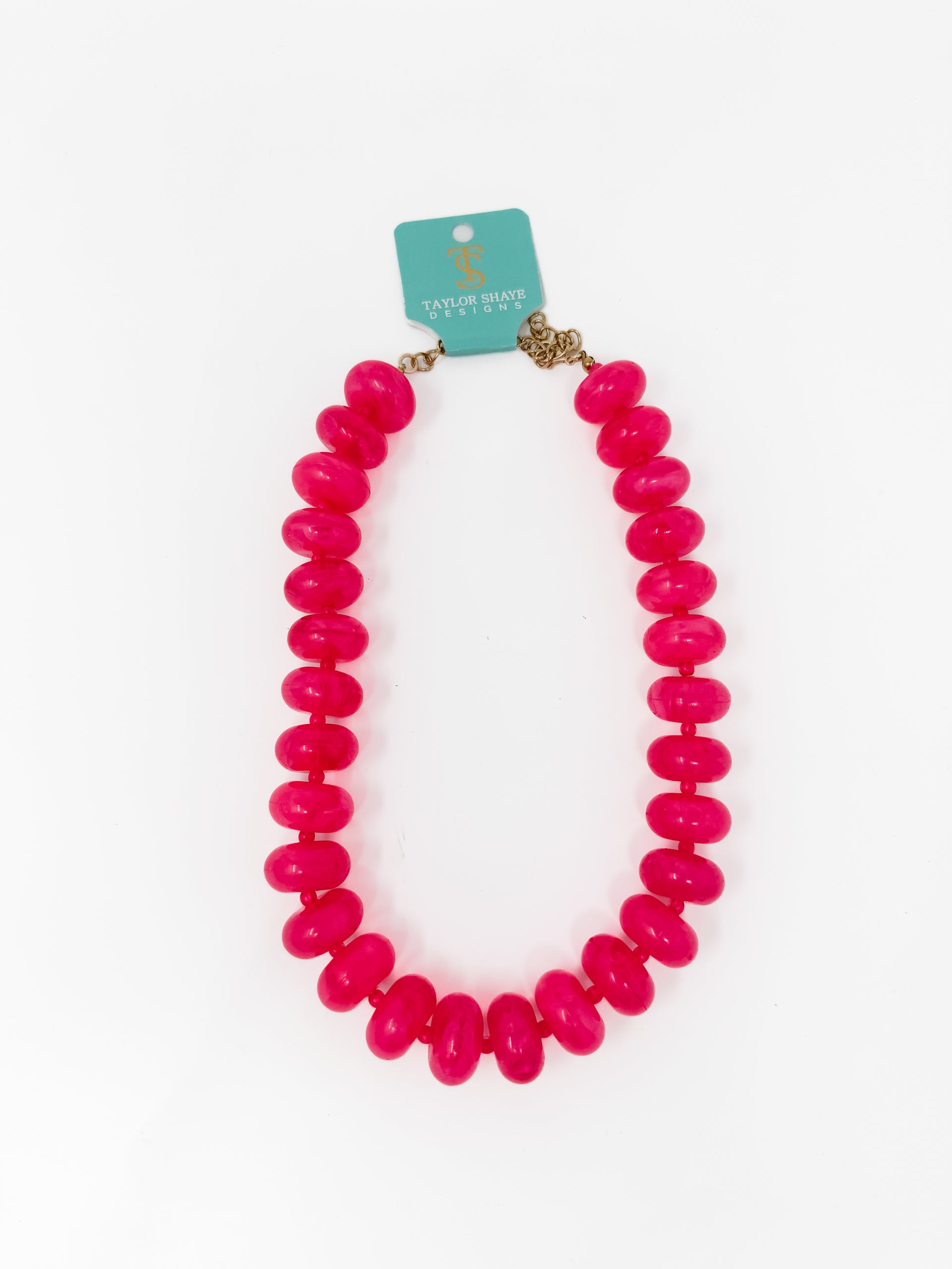 A bright pink chunky beaded necklace with a gold-tone clasp, displayed on a white background with a teal brand tag that reads Taylor Made Jewelry.
