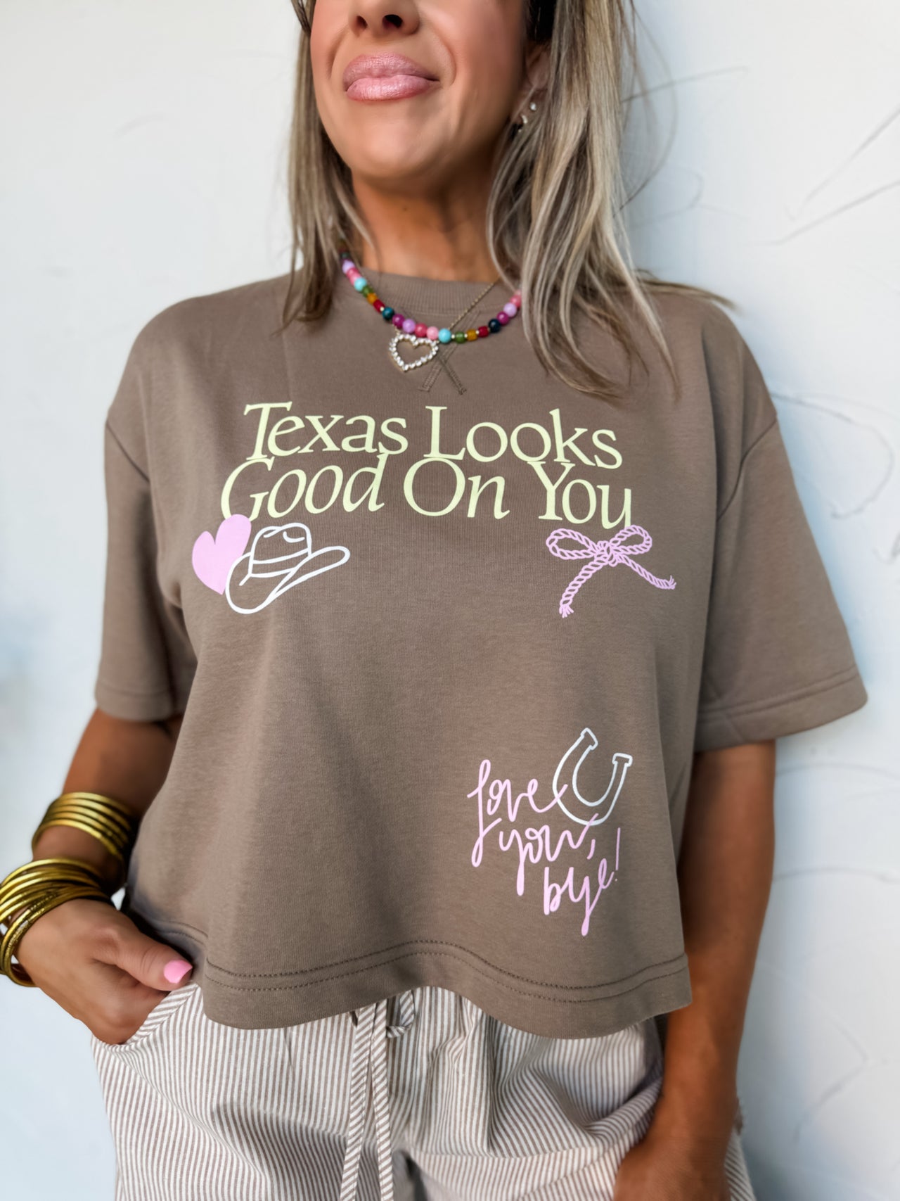 Person wearing a brown t-shirt with text and graphics against a light background