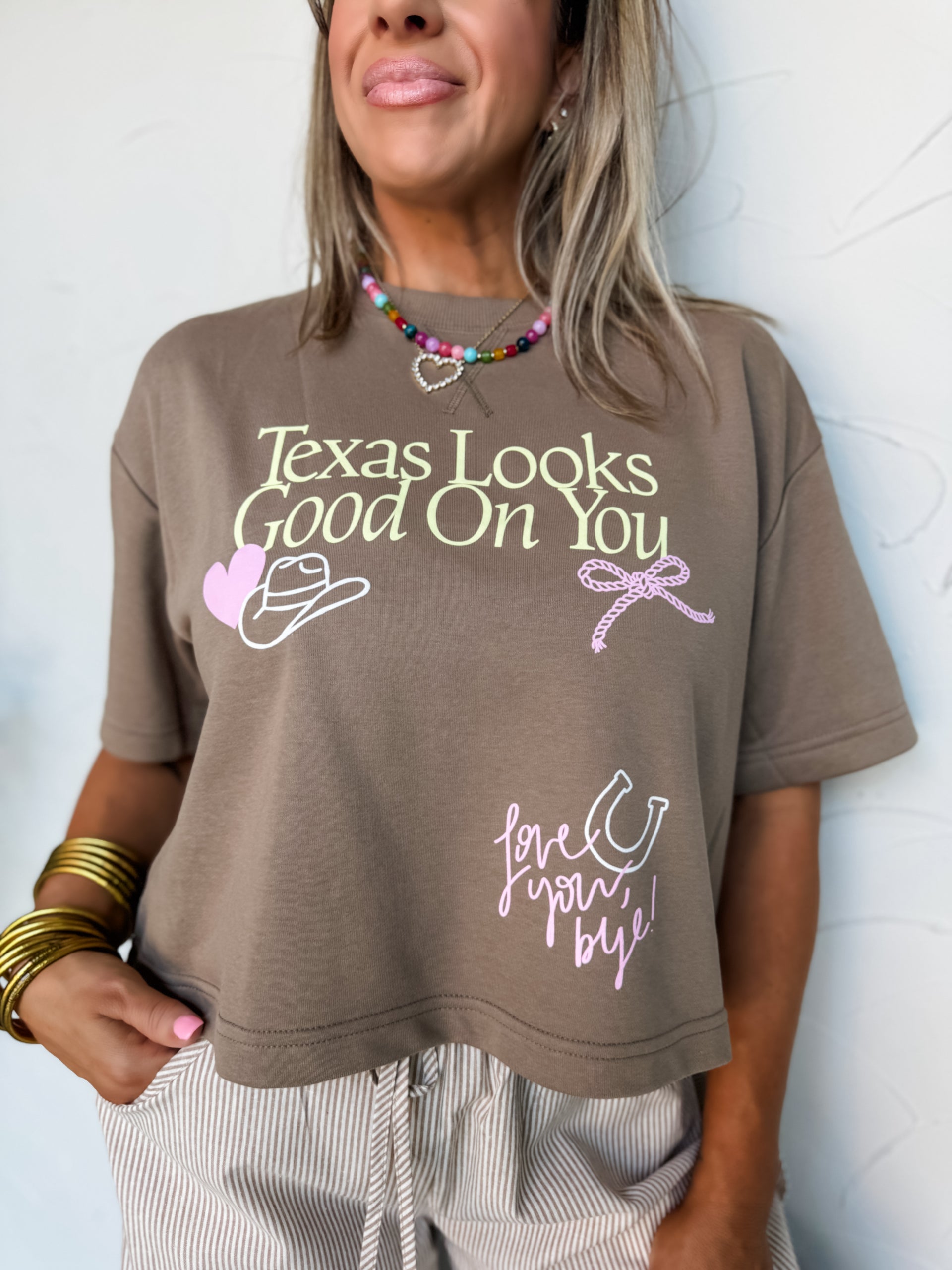 Person wearing a brown t-shirt with text and graphics against a light background