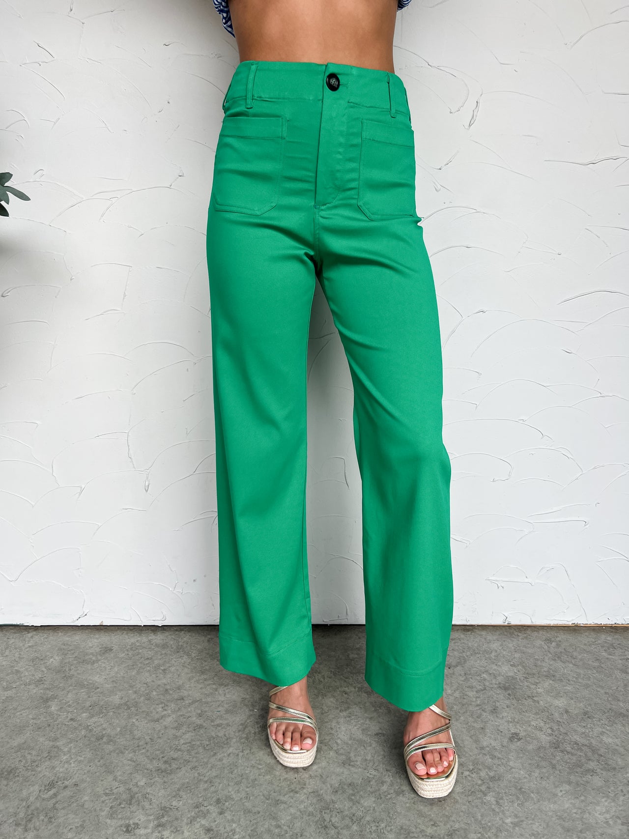 Green pants worn by a person against a white wall.