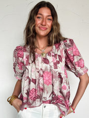 Woman wearing a floral blouse with pink flowers on a white background