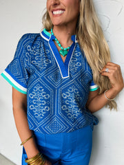 Woman wearing a blue patterned top with white trim against a white background