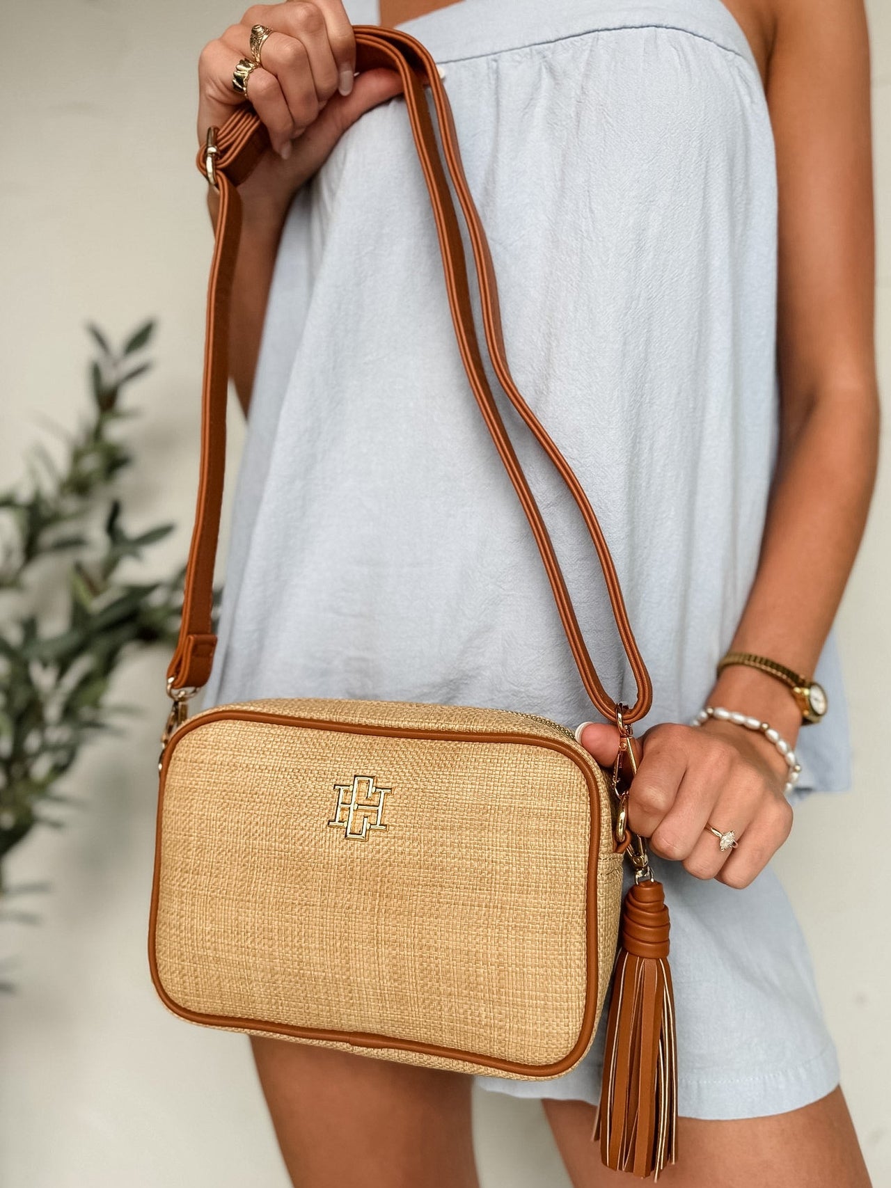 Person holding a woven handbag with a tassel against a neutral background