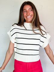Woman wearing a black and white striped sweater and pink pants against a white background