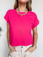 Person wearing a bright pink t-shirt with a white background