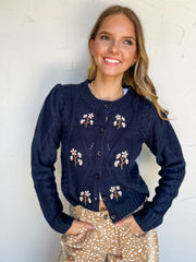 Call Me Lovely Round Neck Sweater in navy by Blu Pepper, made of 100% acrylic with floral embroidery, cable-knit details, long sleeves, and a button front.